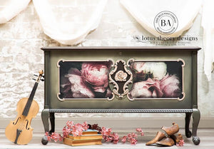 May include: A green painted chest with ornate gold trim and a floral design. The chest is sitting on a white surface with a violin, books, and flowers in front of it. The chest has a sign that reads 'lotus theory designs BOLD FEARLESS SOULFUL FURNITURE & HOME DECOR' and 'PURE BELLE PAINT COMPANY BRAND AMBASSADOR BA'.