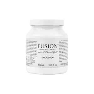 May include: A white Fusion Mineral Paint jar with a white lid. The label reads 'Fusion Mineral Paint' and 'Snowdrop.' The jar contains 500mL and 16.9 fl oz. The label also includes text about the paint's durability and application. The jar is set against a white background.
