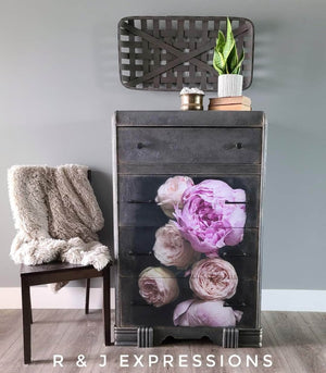 May include: A black dresser with five drawers, each drawer decorated with a floral print of pink peonies. The dresser has a distressed finish and silver accents.